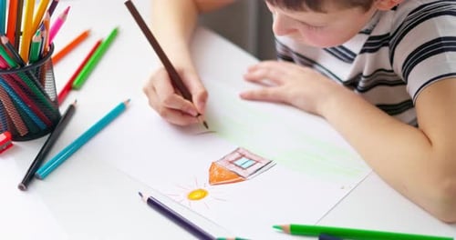 Cute Boy Drawing on a Piece of Paper with Color Pencils at Home or Classroom