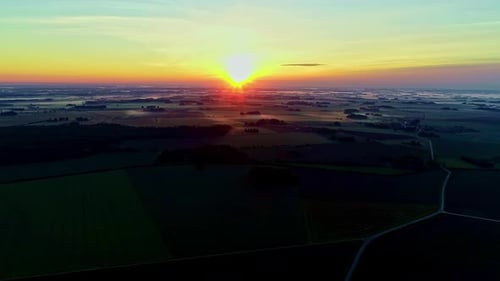 Aerial view over fog covered plains in the morning over the meadow near a rural village with a house
