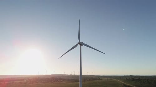 Rotating Wind Turbines Over Mountains In Portugal During Sunset. Tilt-up Shot