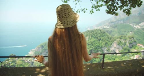 The woman with long hair overlooks a stunning view of the sea and mountains in Ravello town, Italy.