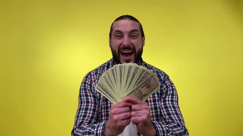 Excited Man Displaying Fan of Money on Yellow