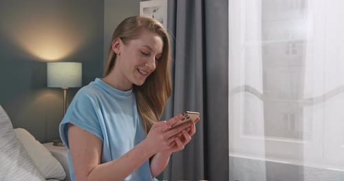 Woman Using Mobile Phone in Bedroom