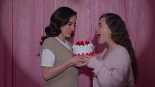 Female Couple Sharing a Strawberry Cake in a Valentine Photo Booth
