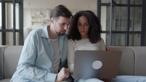 Couple Relaxing on Sofa Using Laptop at Home