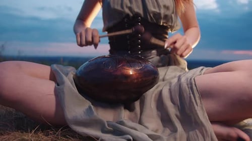Woman Plays Drumsticks on a Steeltongued Drum in the Great Outdoors