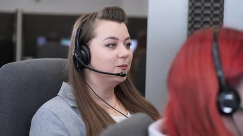 Female Call Center Operator Working with Headset in Busy Office