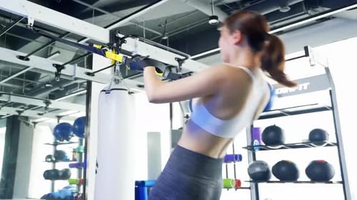 Beautiful sportswoman doing strength exercise suspension training lifting rope equipment sports gym