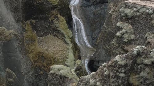 Misty, Powerful Waterfall Plunging into a Clear Pool Amidst Green Cliffs