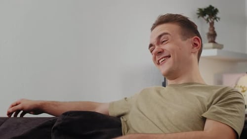 The Guy is Watching TV and Laughing Enjoying the Viewing Experience and Feeling Joyous