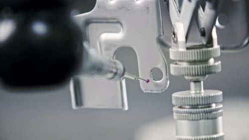 Gros plan d'une aiguille de mesure sur une CNC utilisée pour tester les écarts dans des produits métalliques qui