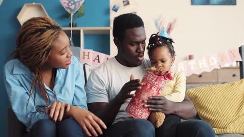 Young Family Opening Birthday Gift in Living Room