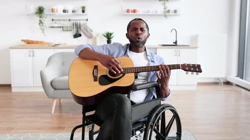 Man in Wheelchair Playing Guitar at Home