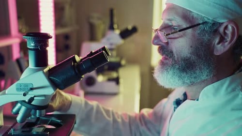 Man Examines Sample with Microscope in Laboratory