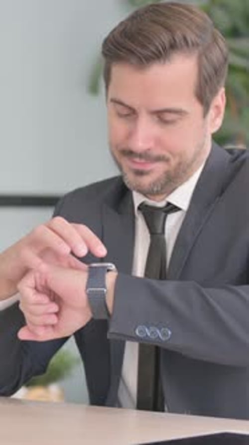 Man in Suit Checks Smartwatch at Office Desk