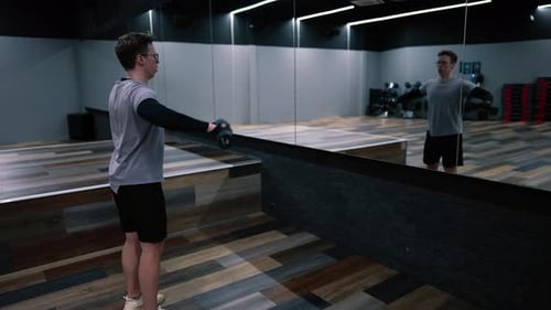 Fitness-Mann trainiert mit Hanteln in einem modernen Fitnessstudio, Armtraining in Zeitlupe