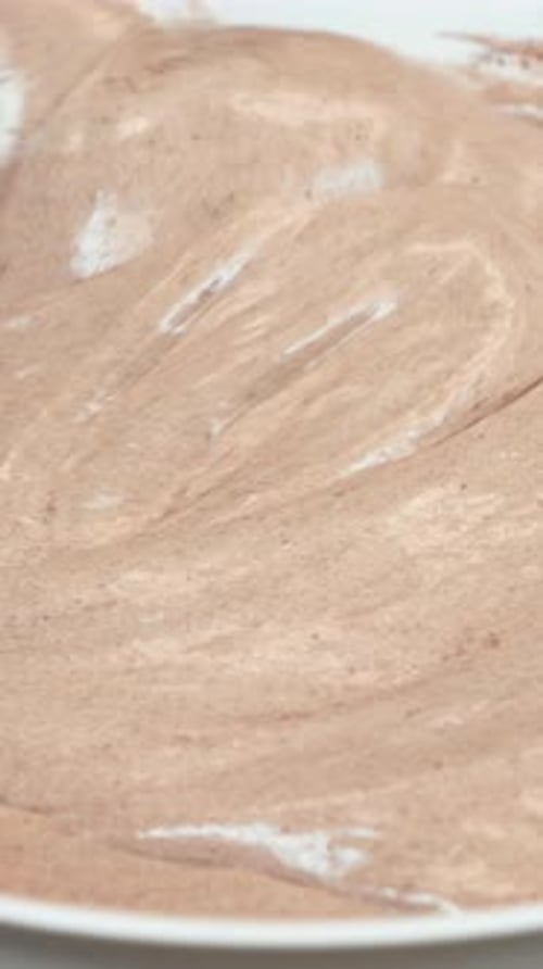 Close up of raw dough for cake in bowl with stirring spatula. Vertical video