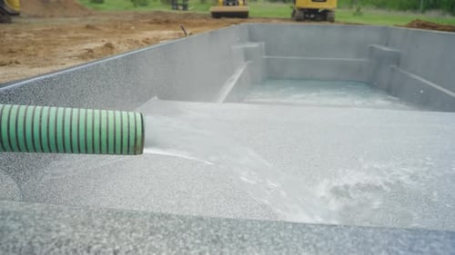 Water Flowing from Green Hose into New Fiberglass Pool During Installation