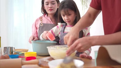 Mother, Father, and Daughter Baking Together at Home