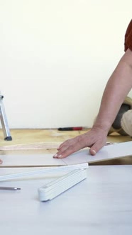 Person Laying Laminate Flooring in Home