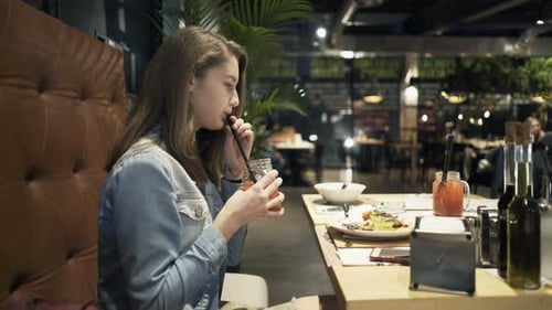 Young girl enjoys a refreshing cocktail at a cafe on a leisurely afternoon