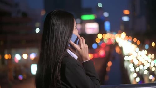 A young beautiful business woman is using smart phone in city over traffic lights