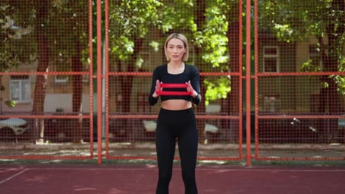 Woman Stretching With A Resistance Band At A Basketball Court