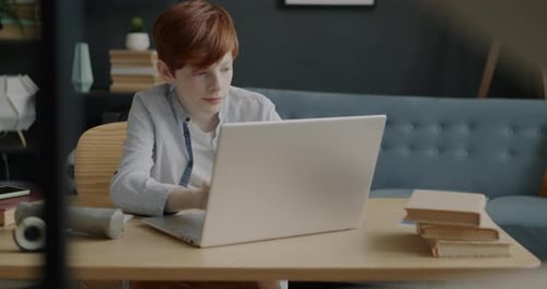 Intelligent Kid Working with Laptop Computer Typing Concentrated on Educational Internet Course at