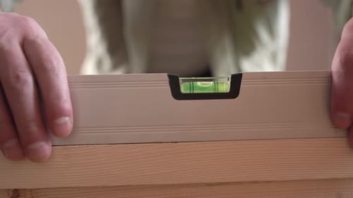 a male craftsman measures the plane with the building level of his working project.