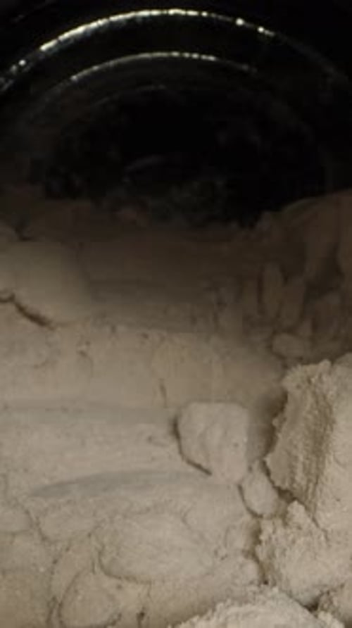 Vertical video. A Large Black Jar With Chocolate Protein Powder That Has Formed Into Hard Clumps.