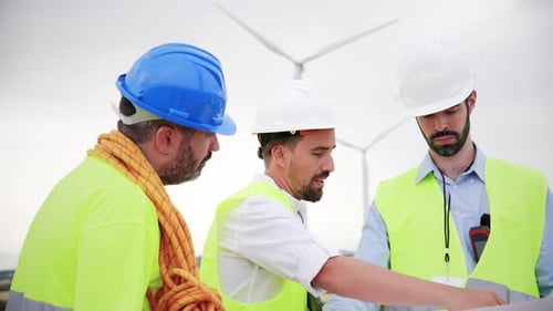 Group of Windmill Engineers Talking About the Construction Watching Plans of the Turbine