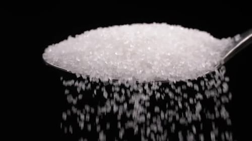 spoon full of powdered sugar crystals in teaspoon side view filled with sugar