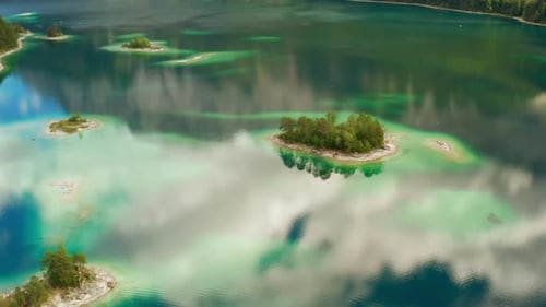 Aerial View of Calm Lake with Reflected Clouds and Small Islands with Trees