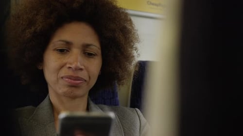 Afro American commuter on her way to work looking at smart phone