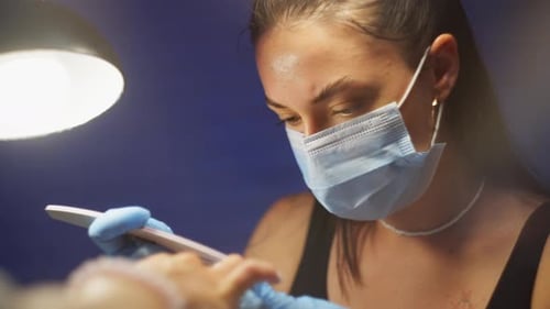 Woman Filing Nails in Salon Wearing Face Mask