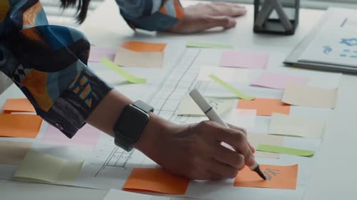 Hands of Woman Drawing on Chart and Stickers in Creative Office Space