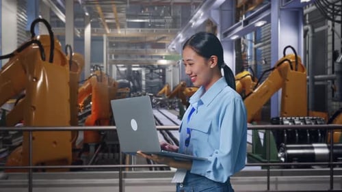 Smiling Woman with Laptop in Modern Factory