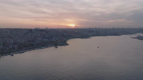 Aerial Panoramic Footage of Metropolis at Dusk Large City on Bank of Wide River Sun Setting Behind