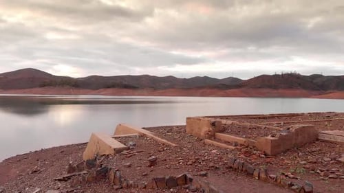 Low water level of a reservoir suffering os a drught. Arade Dam in Algarve, Portugal