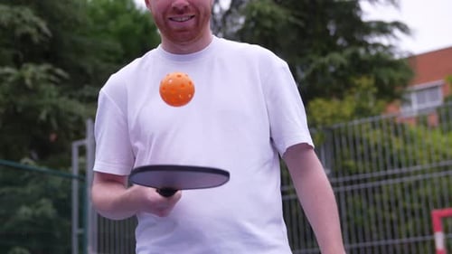 Man Bouncing Pickleball Ball on Paddle Outdoors