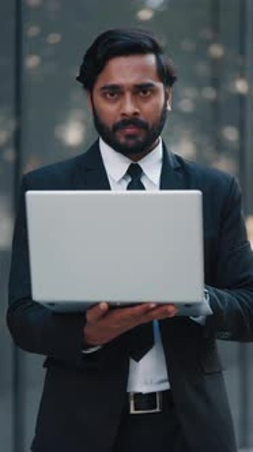 Smiling Businessman Holding Laptop in the City