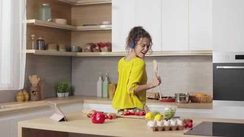 Woman Dancing and Singing with Spoon in Kitchen