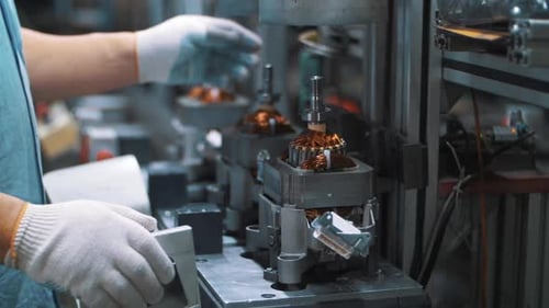 Trabajador industrial ensamblando un motor eléctrico en un equipo automático. Instalación eléctrica de primer plano...