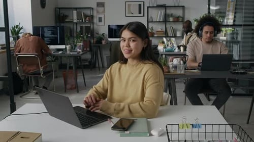 Portrait of Positive Young Woman Programming on Laptop at Workplace