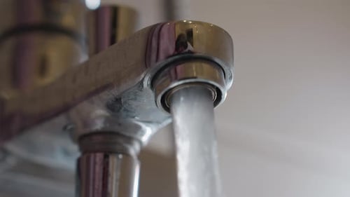 Close Up Water Flowing From Chrome Tap with Reflection