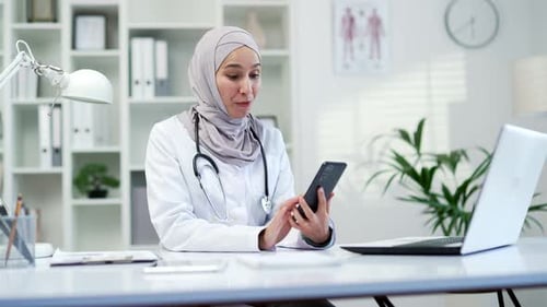 Smiling Doctor Video Calling in Modern Office