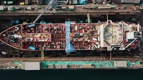 Drone flying above the cargo ship in the shipyard docks