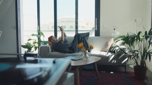 Young Adult Relaxing on Couch with Smartphone