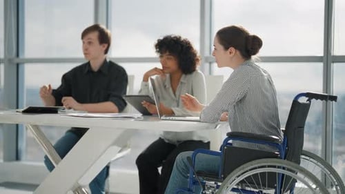 Corporate Colleagues Working on Project in Office Together Sitting at Desk Woman in Wheelchair with