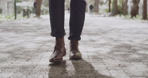 Feet of a fashionable business man walking, taking steps forward in a city