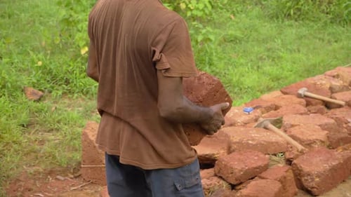 Adult Man Building Stone Retaining Wall in Garden